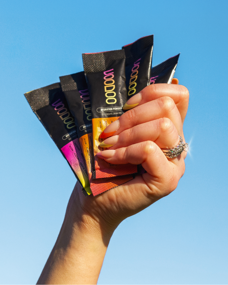 Hand holding multiple colorful packets against a clear blue sky