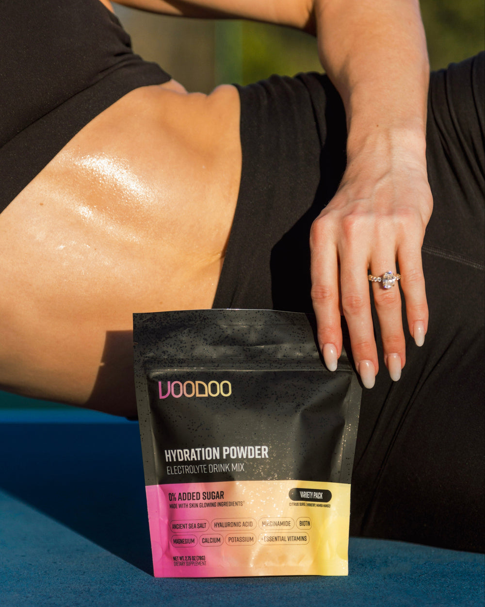 Person holding a package of VooDoo Hydration Powder on a blue surface